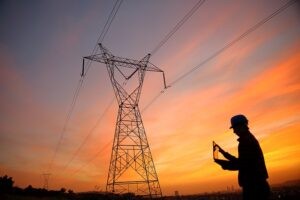 Electrical engineer working laptop at electric tower